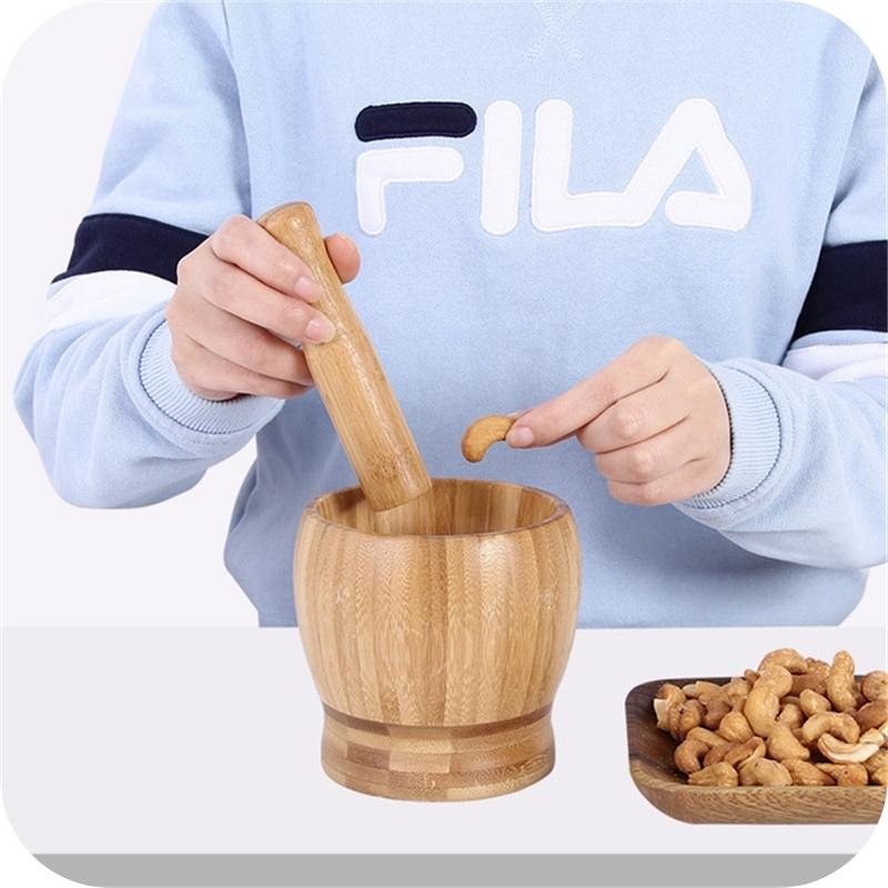 Showing adding a peanut to the Three Large and Three Small Wooden Bowls Grinder Crusher for Guacamole Pepper Garlic