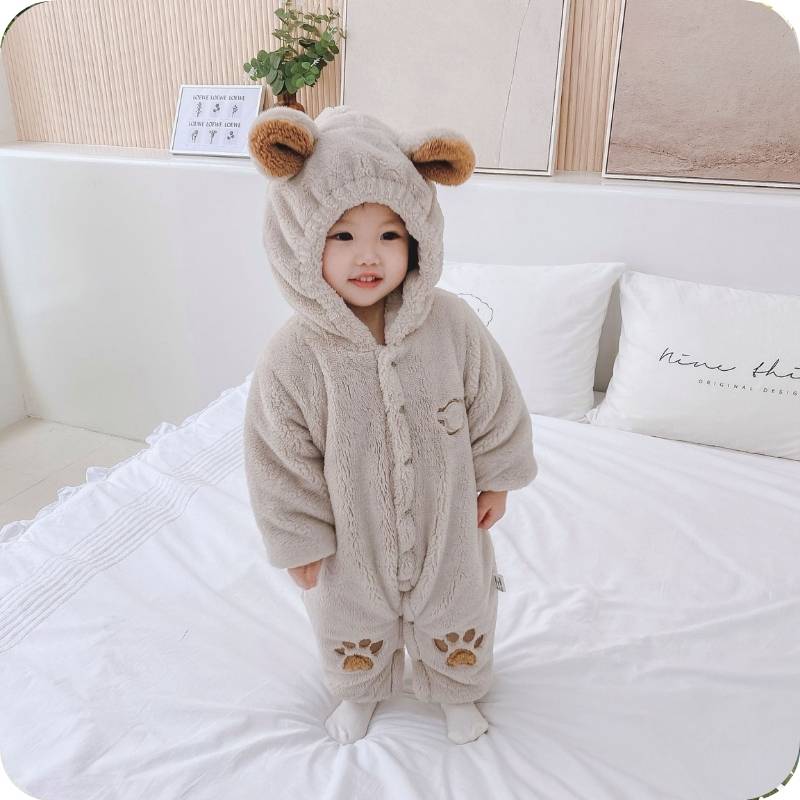 Child wearing a fluffy bear onesie on a white couch