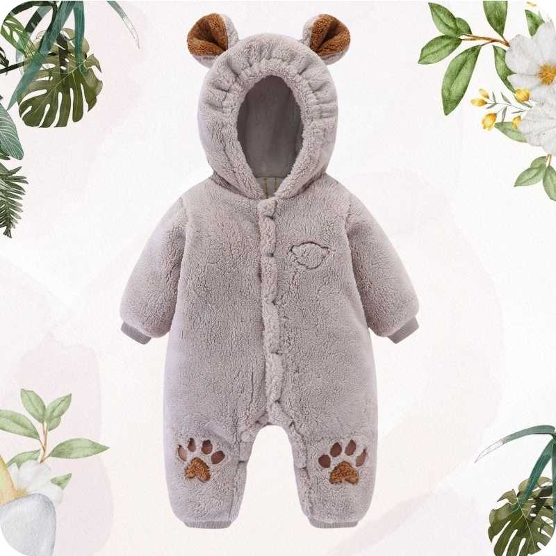 Gray baby snowsuit with bear ears and paws on a light pink background with greenery.