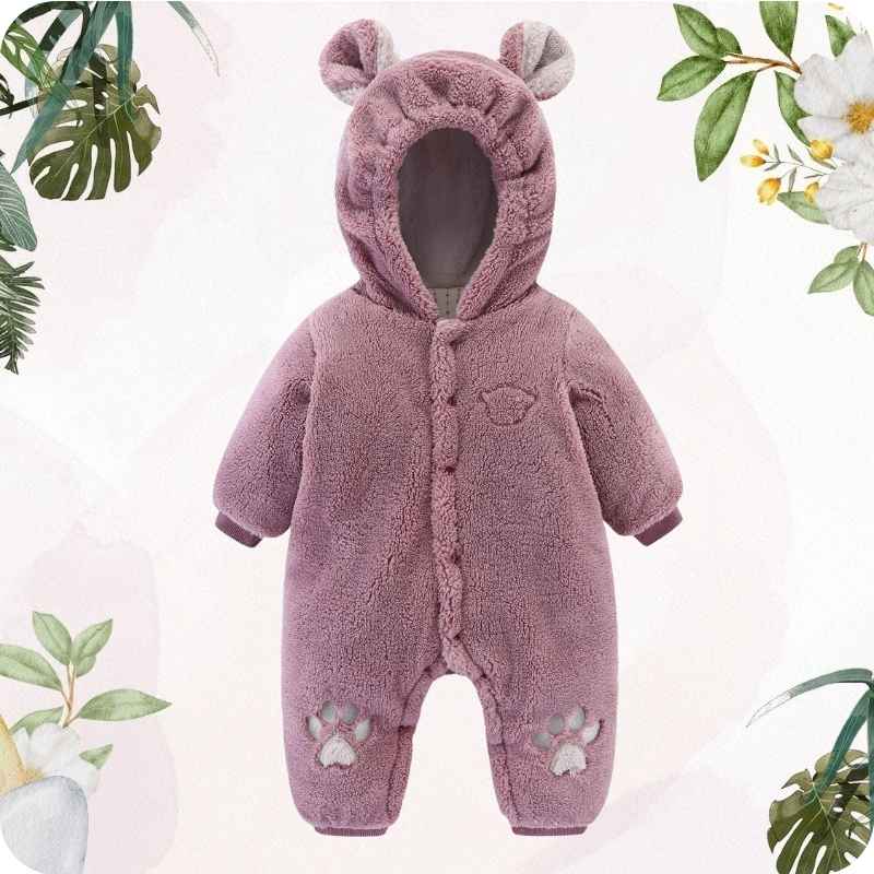 Pink baby snowsuit with bear ears on a light pink background with green leaves.