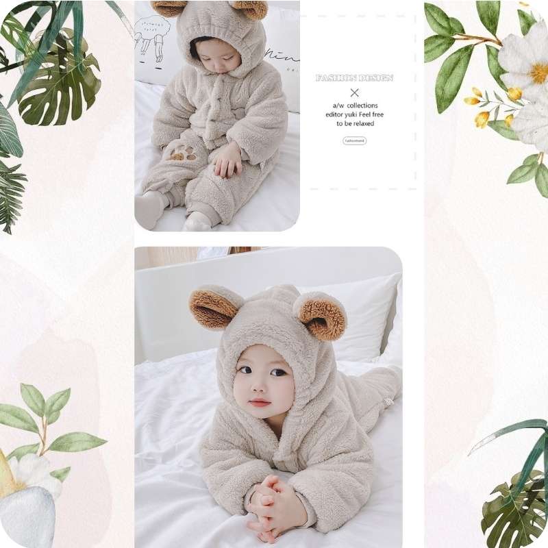Child wearing a fluffy bear onesie on a white blanket with decorative plants around.