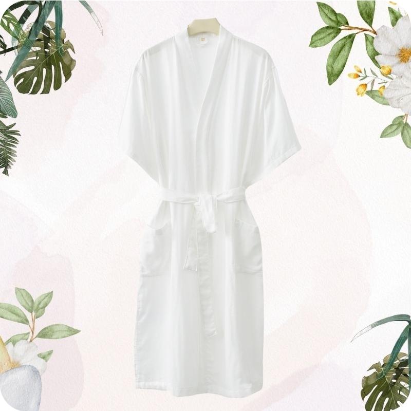 White robe on a hanger with floral and leaf decorations on a light pink background