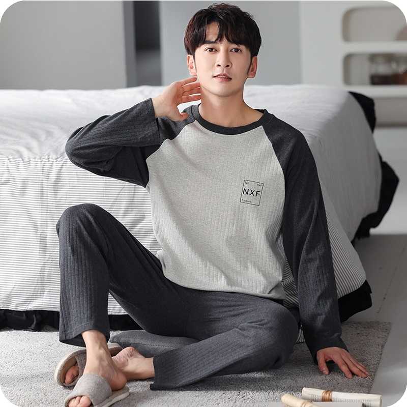 Man wearing a gray and black pajama set sitting on a couch.