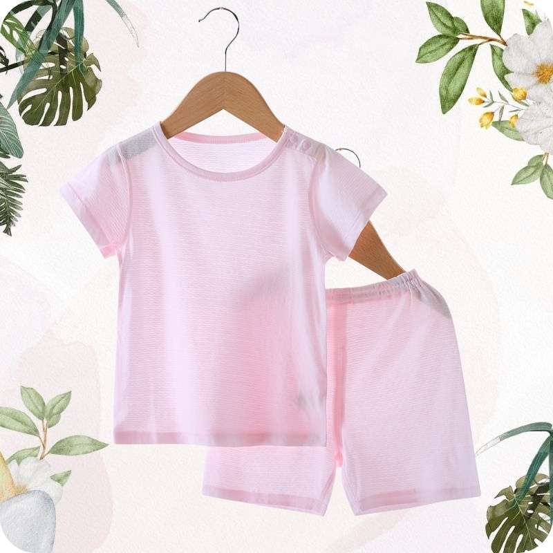 Pink children's shirt and shorts set on a hanger with a floral and leafy background.