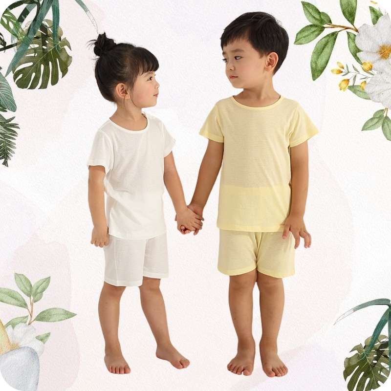 Two children holding hands wearing matching pajama sets with a floral and leafy background.