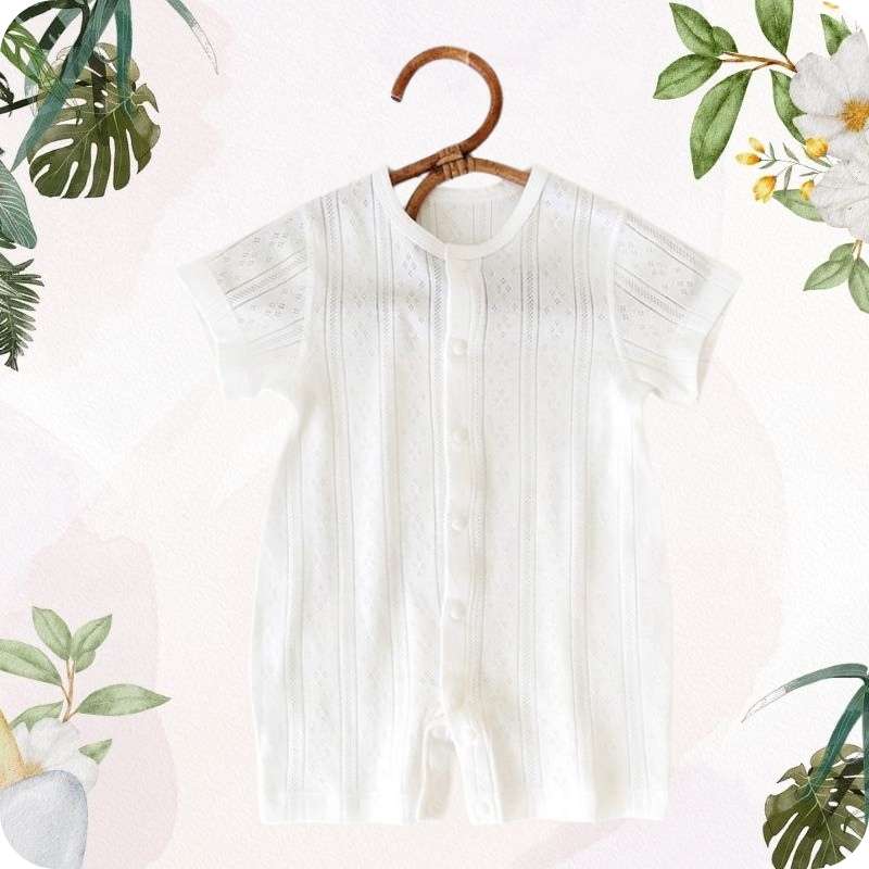 White baby romper on a wooden hanger with floral and leaf decorations.