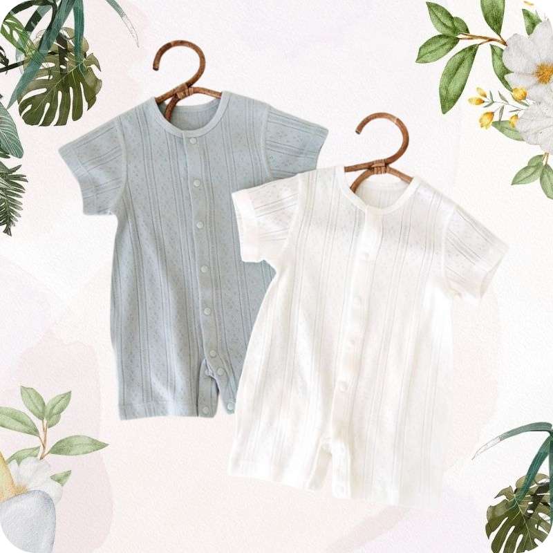 Two baby rompers on hangers with a floral and leafy background