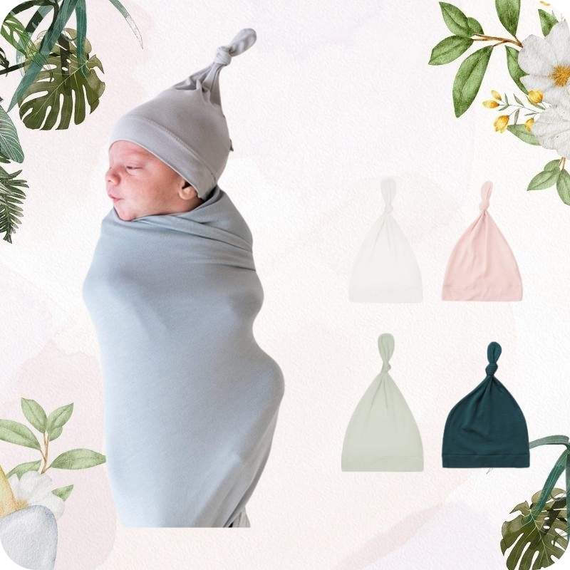 Newborn baby swaddled in gray blanket with matching hat, surrounded by floral and leaf elements.