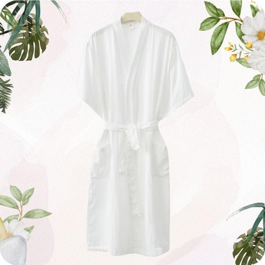 White robe on a hanger with floral and leaf decorations on a light pink background