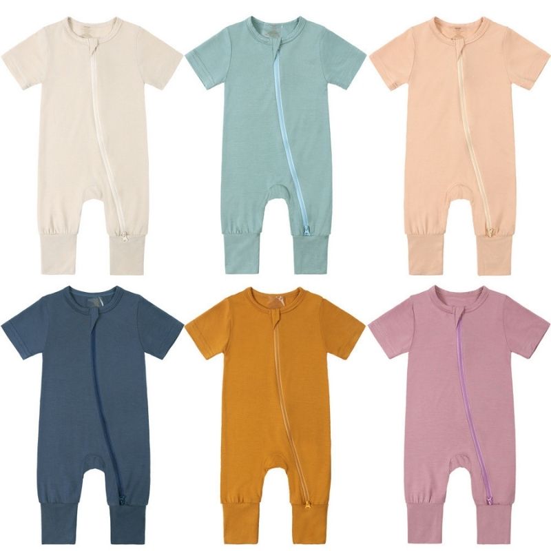 Collection of bamboo baby jumpsuits in soft tones—Ginger Yellow, Coral Pink, Light Green, Light Grey, Light Purple, and Beige. Displayed flat with short sleeves; breathable, ultra-soft, and designed for sensitive skin.