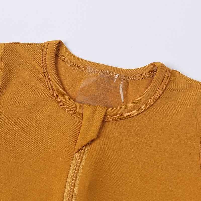 Close-up of a mustard yellow garment with a clear label on a white background