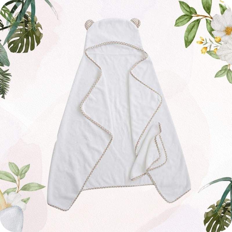 White towel with bear ears on a light pink background with green leaves and flowers.