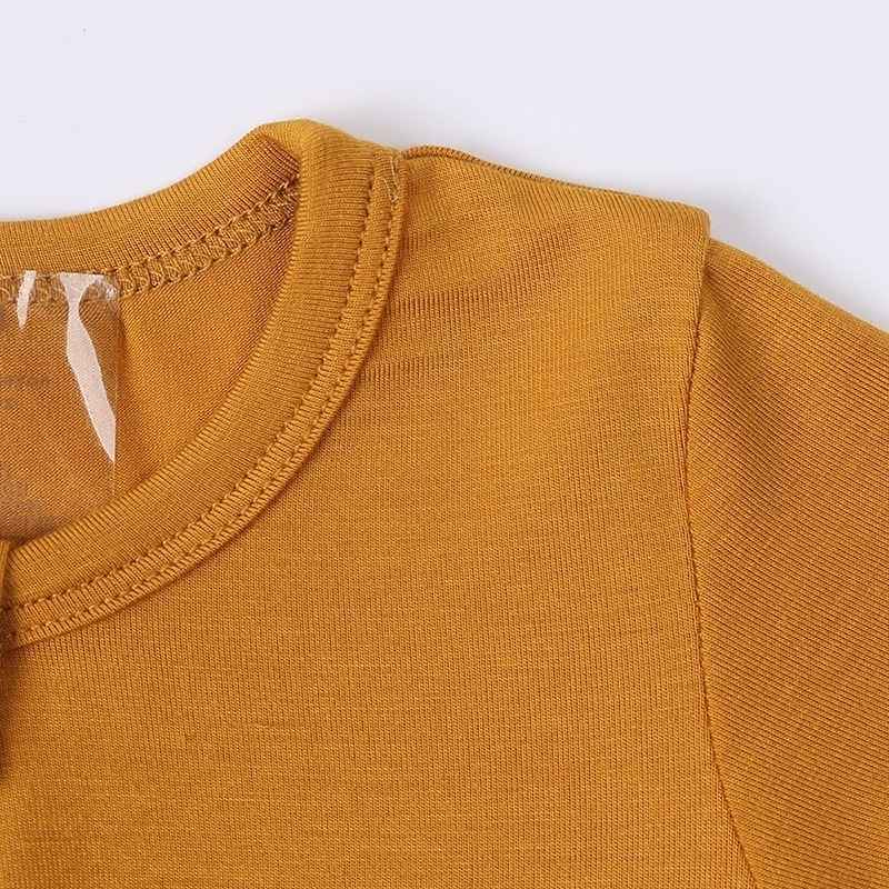 Close-up of a mustard yellow garment with a visible brand label on a white background