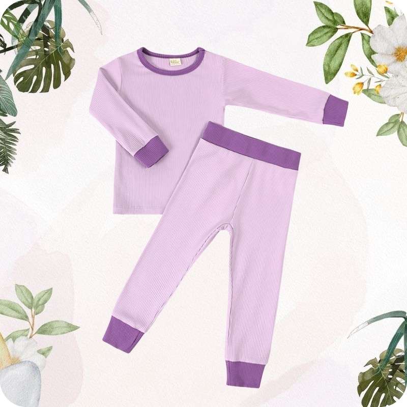 Purple children's pajama set with green leaves and flowers in the background