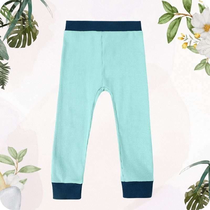 Teal ribbed pants with navy cuffs on a light pink background with floral decorations
