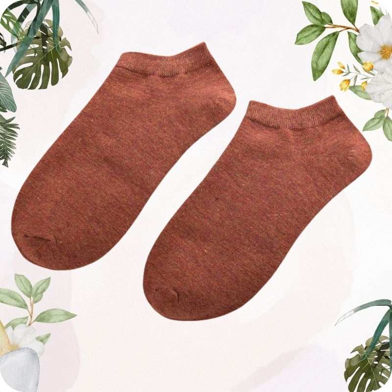 Pair of light brown ankle socks on a light background with green foliage.