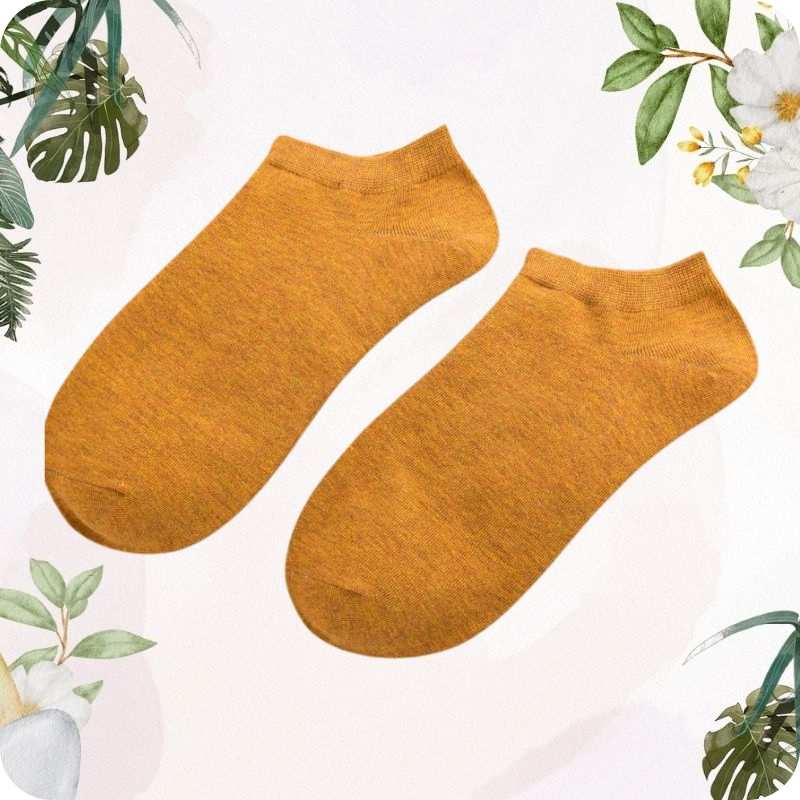 Pair of yellow socks on a light background with floral and leaf decorations.