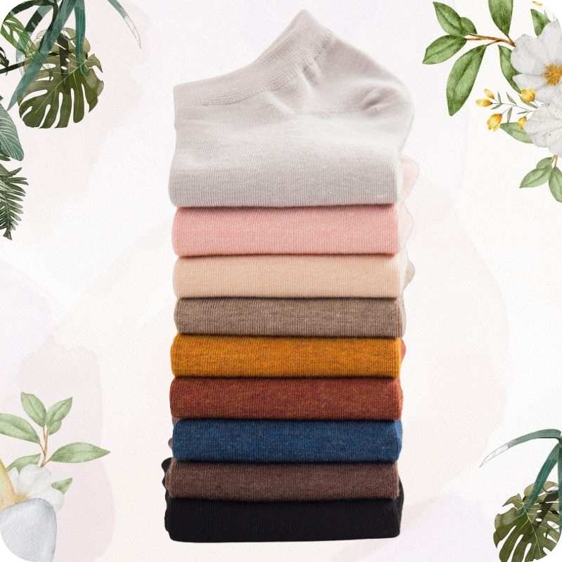 Stack of folded socks in various colors with a soft white background and greenery.