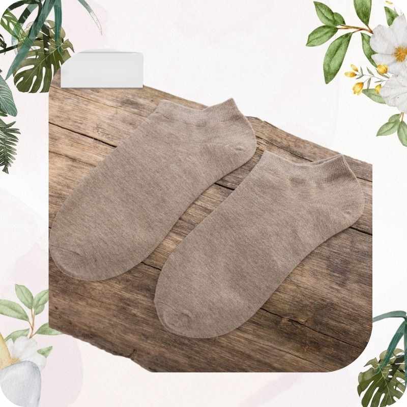 Two light brown socks on a wooden surface with floral decorations.