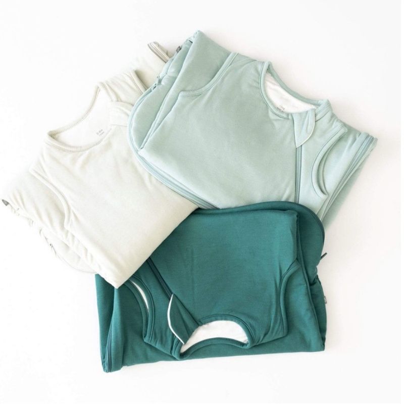 Three folded sleeping bags in white, green, and blue on a white background
