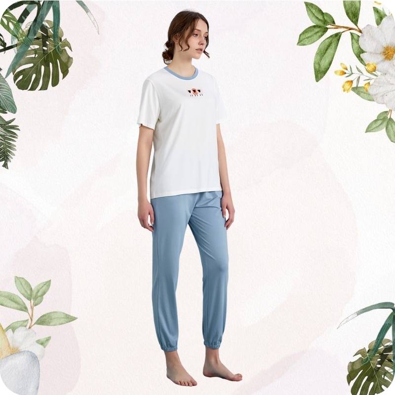 Woman wearing a white t-shirt and light blue pants on a white background with floral and plant elements.