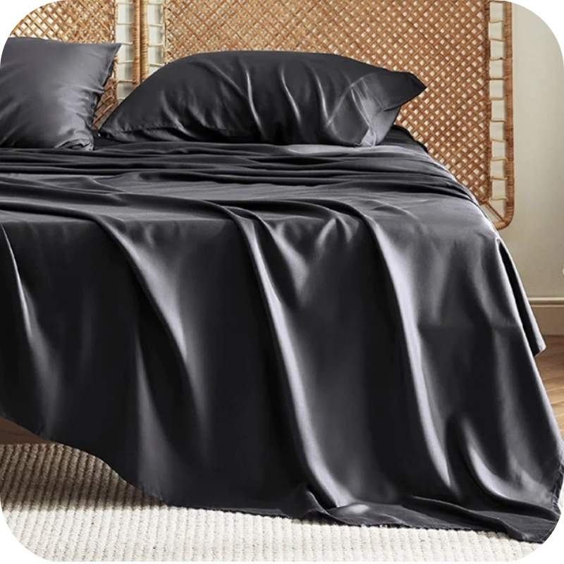 A black bamboo fiber bed sheet set on a bed, including a fitted sheet, pillowcase, and two additional pillowcases.