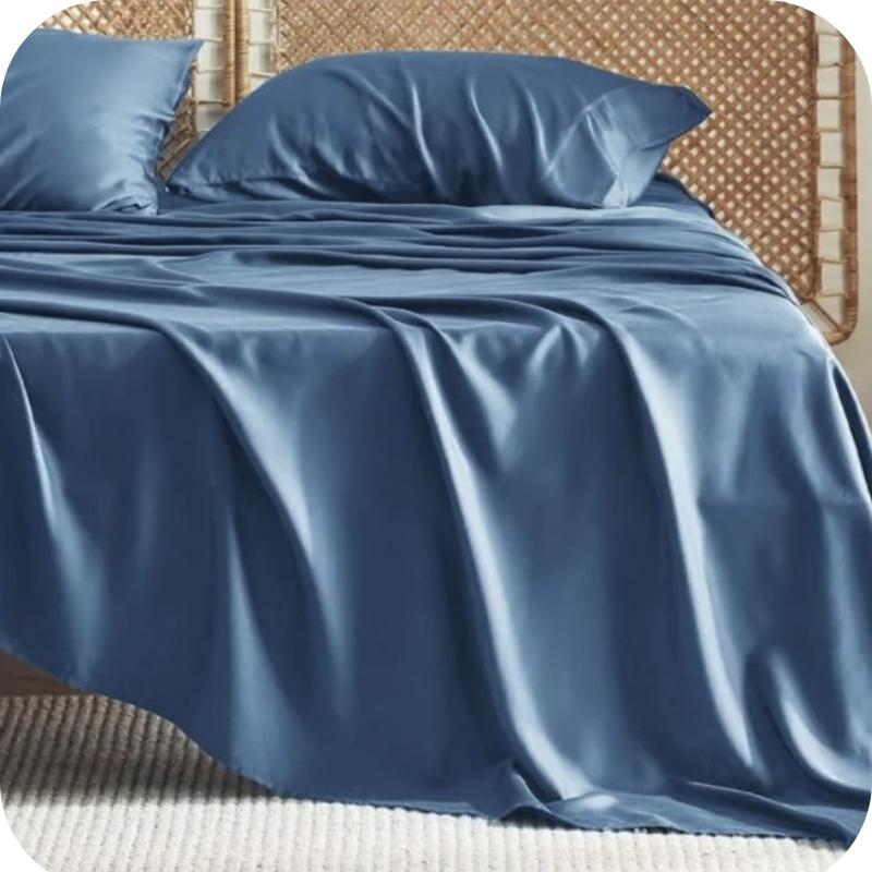 A blue bamboo fiber bed sheet set on a bed, including a fitted sheet, pillowcase, and two additional pillowcases.