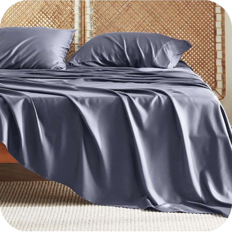 A dark grey bamboo fiber bed sheet set on a bed, including a fitted sheet, pillowcase, and two additional pillowcases.