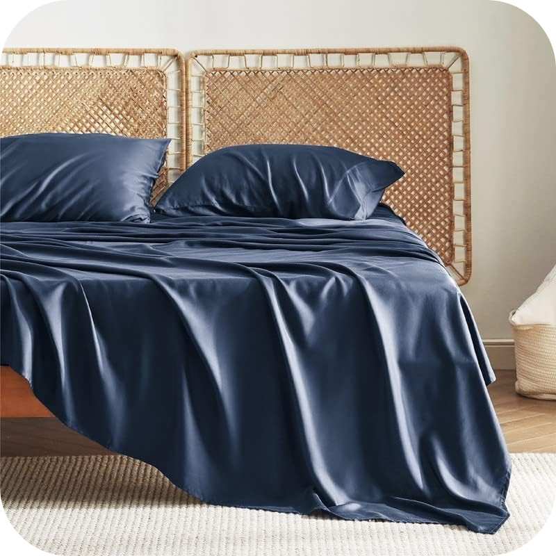 A navy-blue bamboo fiber bed sheet set on a bed, including a fitted sheet, pillowcase, and two additional pillowcases.