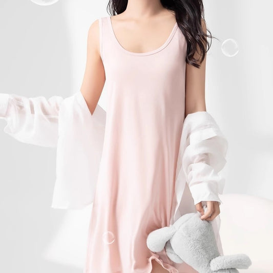 Person wearing a light pink sleeveless top and white pants holding a gray plush toy on a plain background