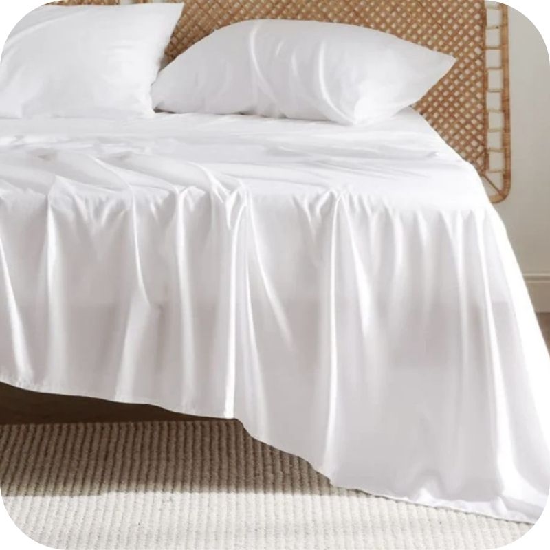 A white bamboo fiber bed sheet set on a bed, including a fitted sheet, pillowcase, and two additional pillowcases.